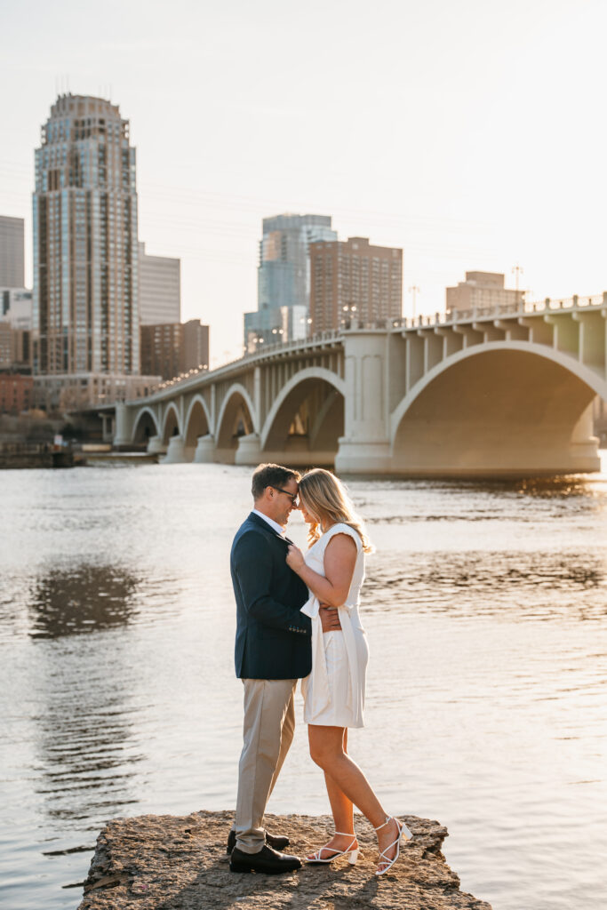 Picture of couple standing in front of the river in St. Anthony Main, Minneapolis. 